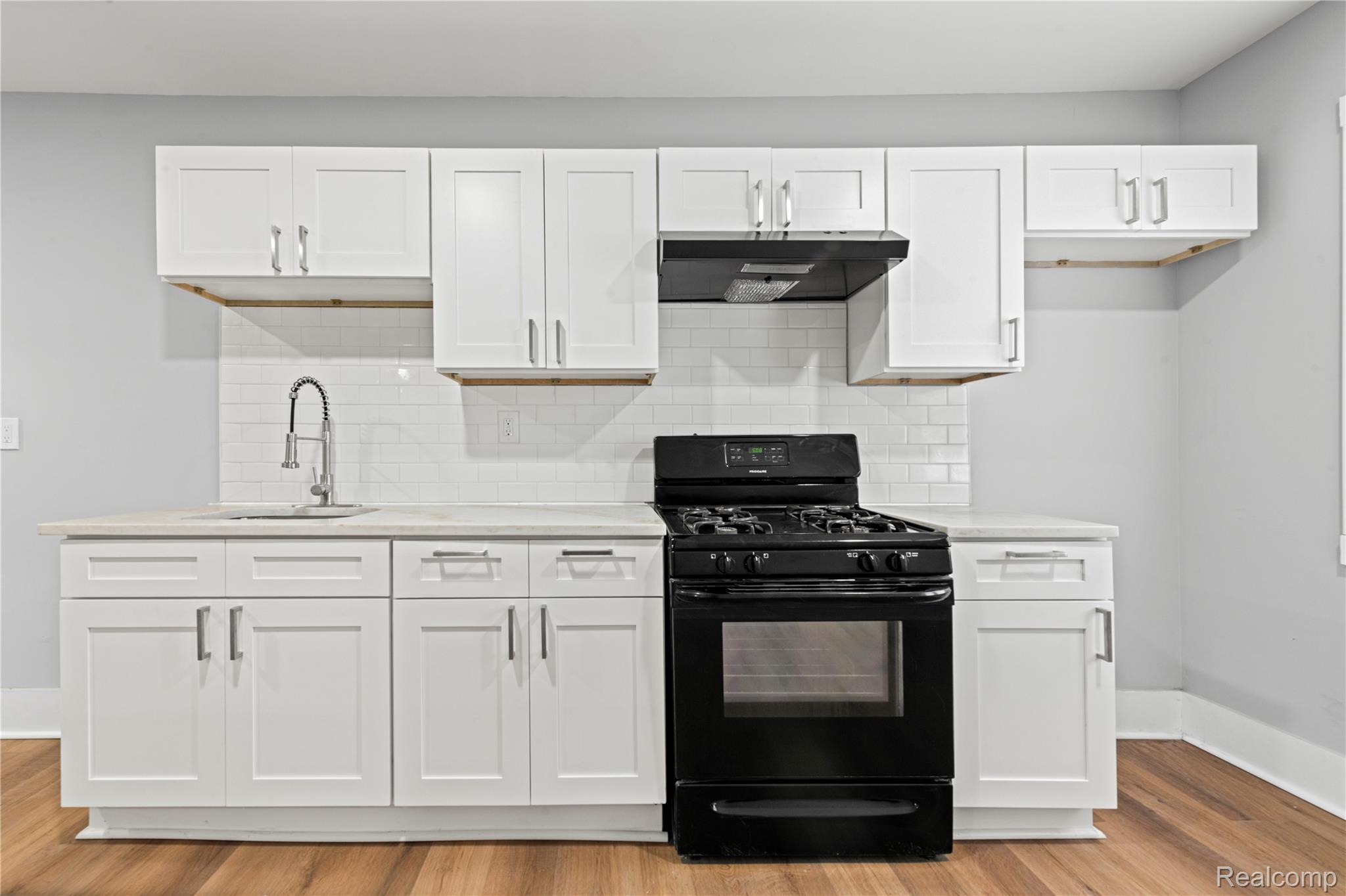 9175 Devonshire Road Detroit, MI 48224 - Photo 9 of 26 Contemporary kitchen featuring white shaker cabinetry, light-toned countertops, a white subway tile backsplash, a black gas range, and wood-finish flooring