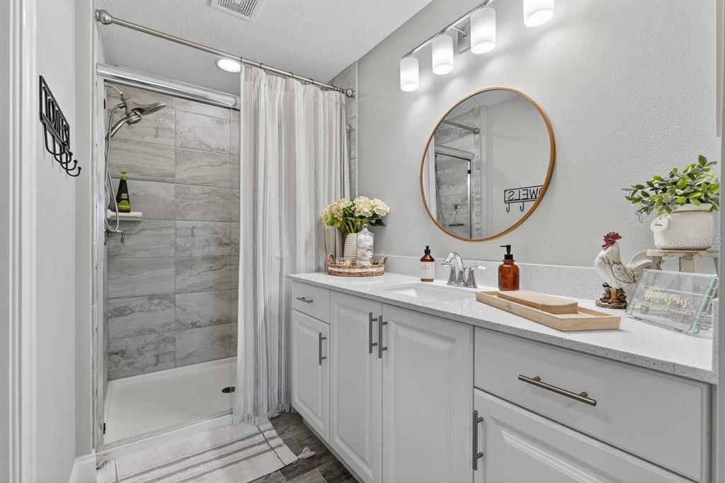 3417 Gallia Street New Smyrna Beach, FL 32168 - Photo 35 of 52 a bathroom with a granite countertop sink a mirror a vanity and a shower