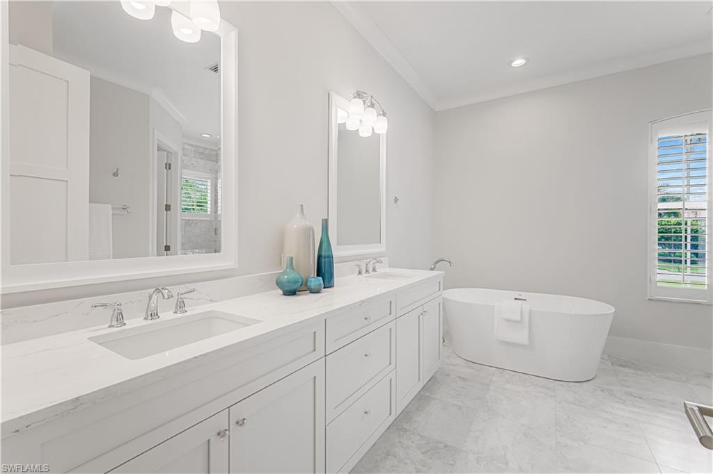 425 Rudder Road Naples, FL 34102 - Photo 14 of 31 a bathroom with a double vanity sink a large mirror and bathtub
