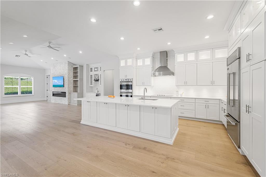 425 Rudder Road Naples, FL 34102 - Photo 17 of 31 a large white kitchen with kitchen island a sink a center island stainless steel appliances and a counter top space