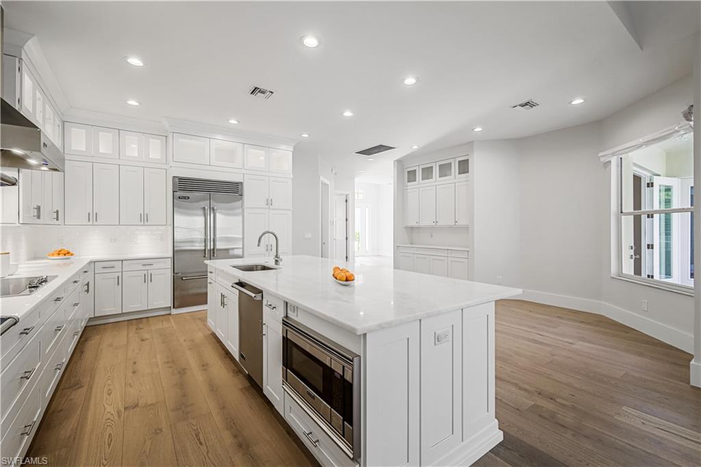 425 Rudder Road Naples, FL 34102 - Photo 21 of 31 a kitchen that has a lot of white cabinets and wooden floor