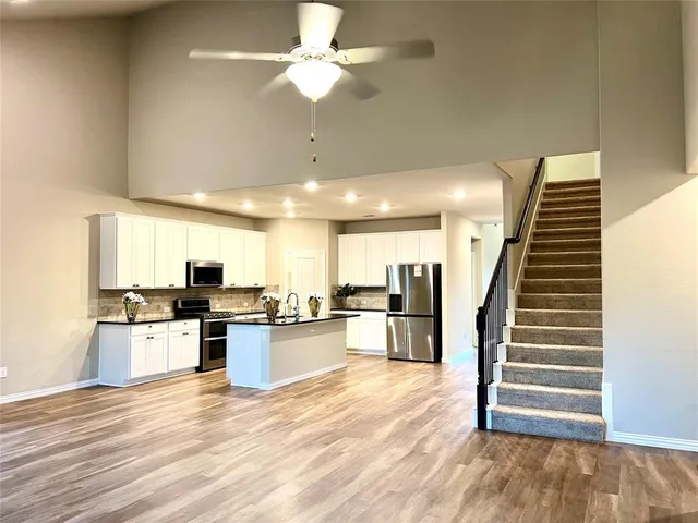 a kitchen with stainless steel appliances kitchen island granite countertop a stove top oven a sink with wooden floors