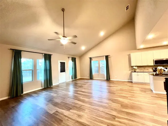 a view of an empty room with window and wooden floor