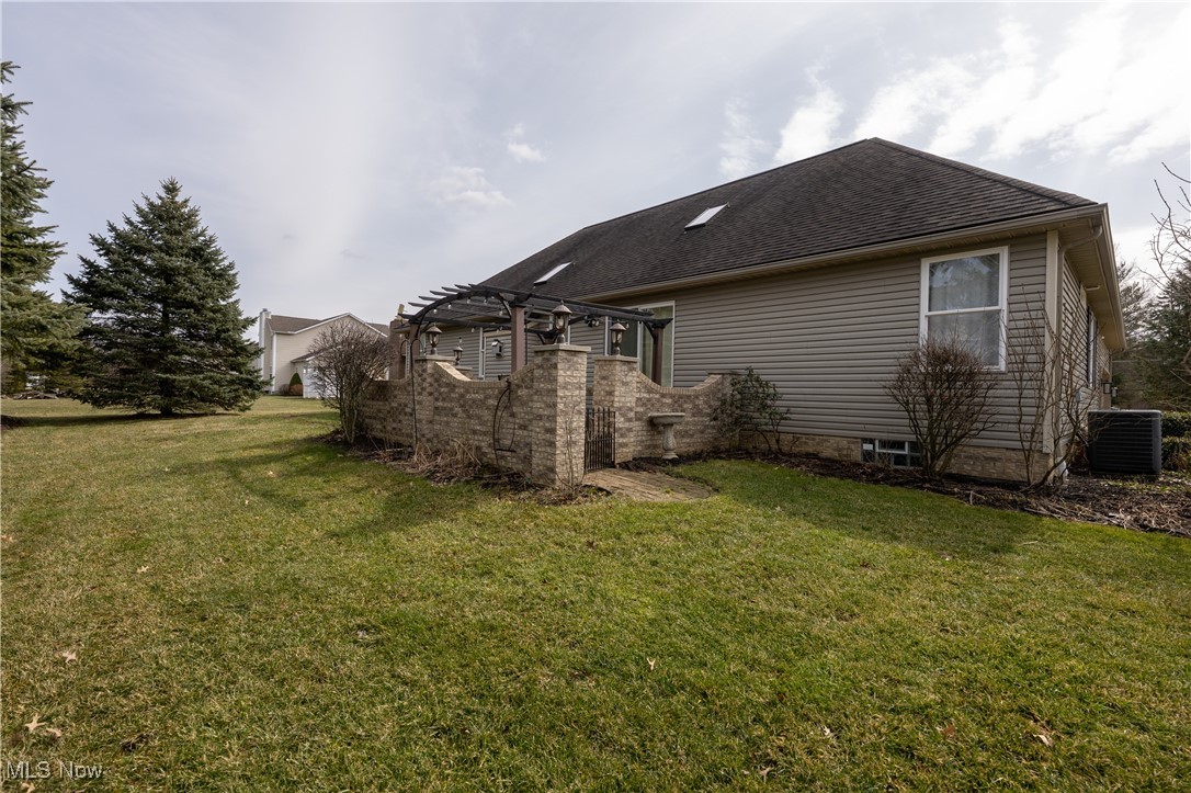 847 Lockwood Road Barberton, OH 44203 - Photo 8 of 29 View of property exterior featuring a lawn, a pergola, central AC, and roof with shingles