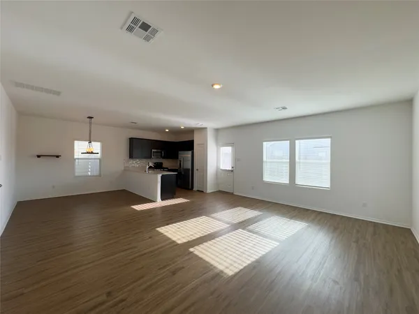 a view of empty room with wooden floor and window