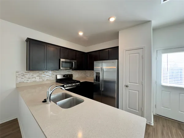 a kitchen with a refrigerator a sink a stove a microwave and wooden cabinets