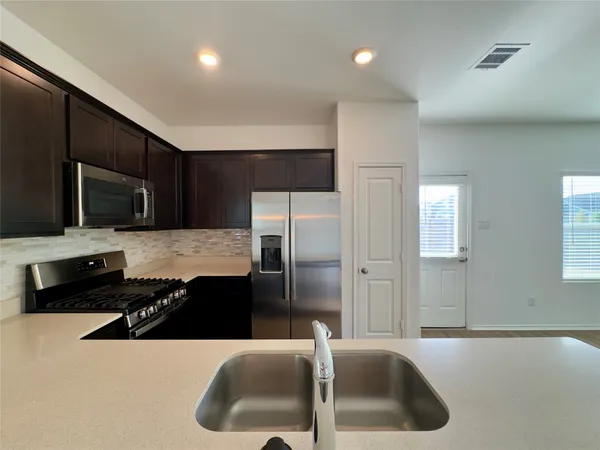 a kitchen with stainless steel appliances granite countertop a sink and a refrigerator