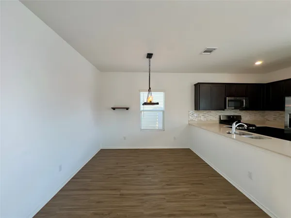 a room with a window wooden floor and a view of kitchen
