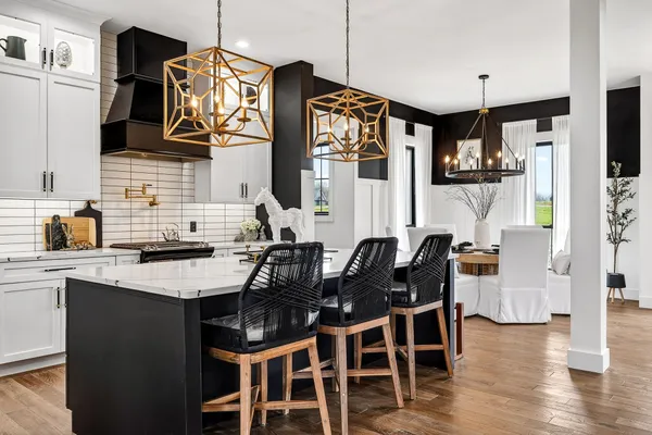 a kitchen with stainless steel appliances granite countertop a stove a sink dishwasher a dining table and chairs with wooden floor