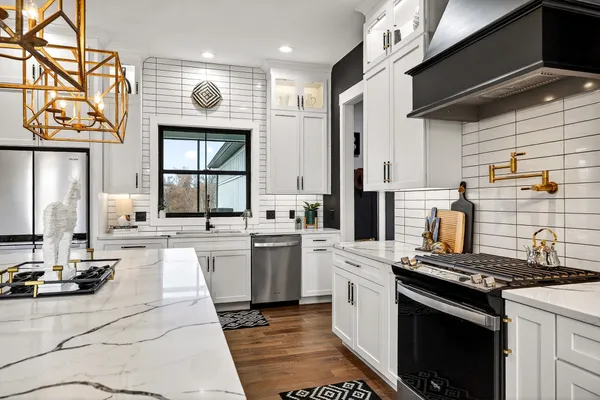 a large kitchen with stainless steel appliances granite countertop a stove a sink and a microwave