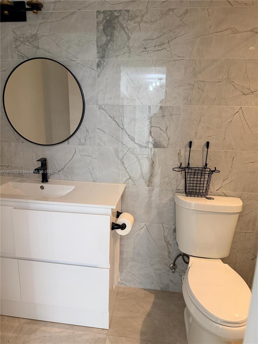911 79th Terrace, Unit B Miami Beach, FL 33141 - Photo 4 of 9 a bathroom with a toilet a sink and mirror