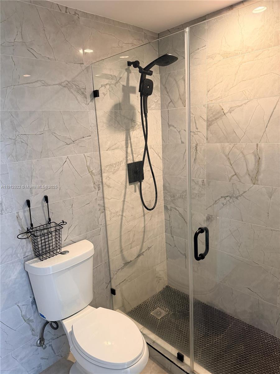 911 79th Terrace, Unit B Miami Beach, FL 33141 - Photo 5 of 9 a white toilet sitting next to a bath tub and shower