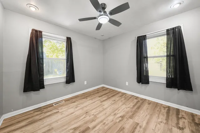 a view of an empty room with a window and a ceiling fan