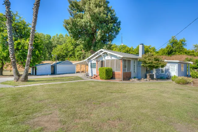 a front view of a house with a garden and tree