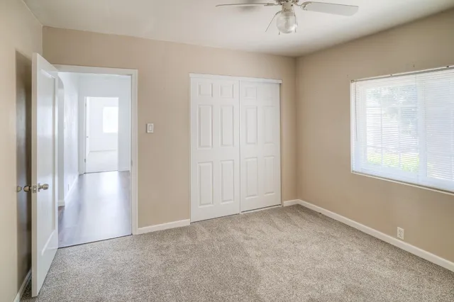 an empty room with windows and fan