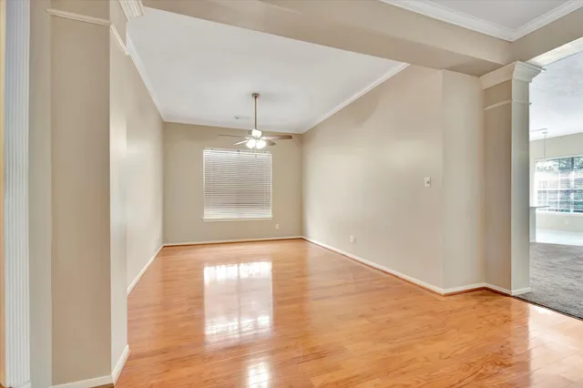 an empty room with wooden floor chandelier and windows