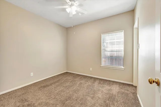 an empty room with a chandelier fan and windows