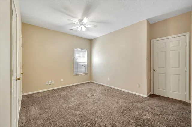 a view of an empty room with chandelier fan