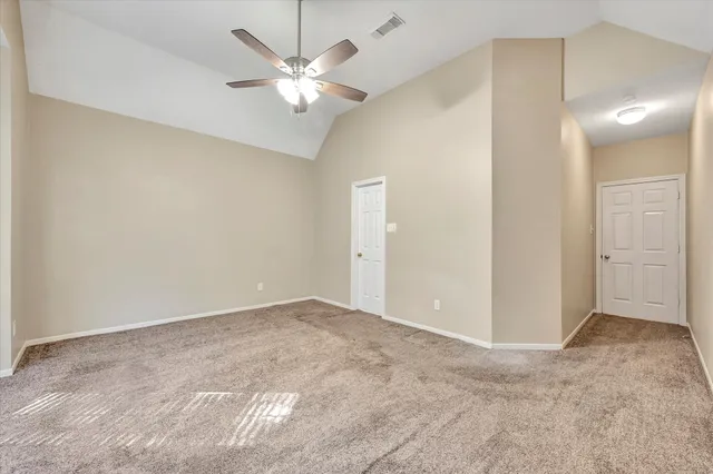 an empty room with a chandelier fan and windows