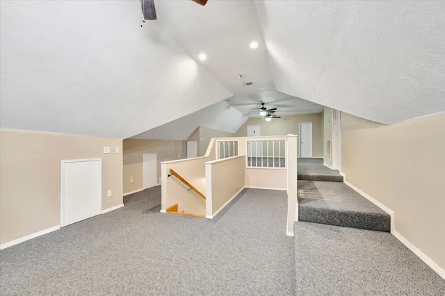 an empty room with chandelier fan and windows
