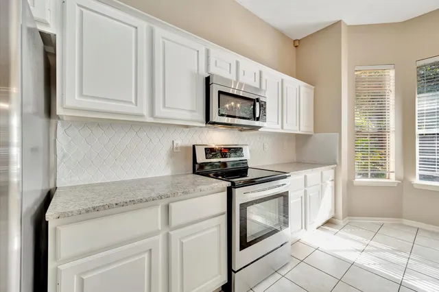 a kitchen with white cabinets and black appliances