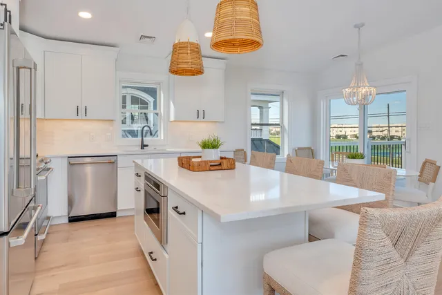 a kitchen that has a lot of white cabinets and stainless steel appliances