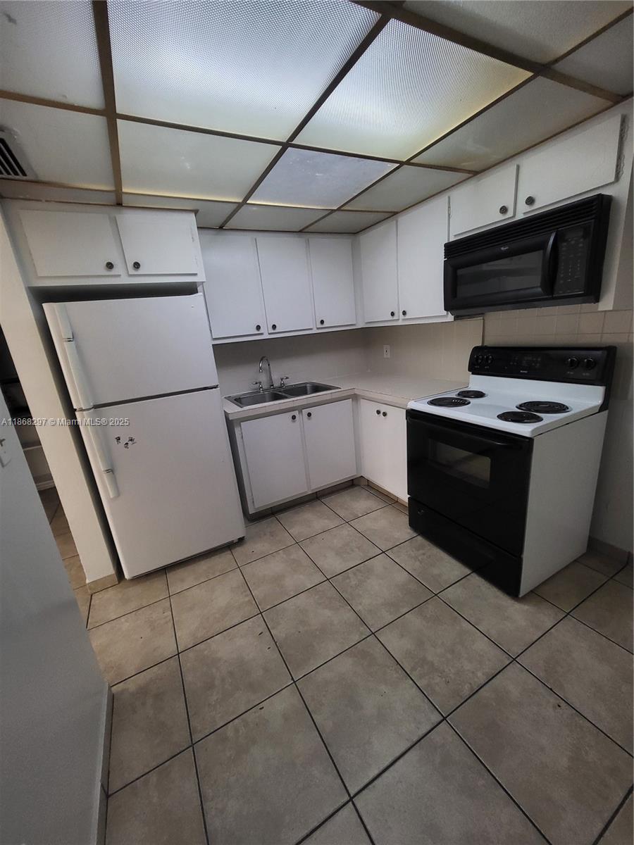 1175 Normandy Drive, Unit 2D Miami Beach, FL 33141 - Photo 3 of 13 a kitchen with a sink appliances and cabinets