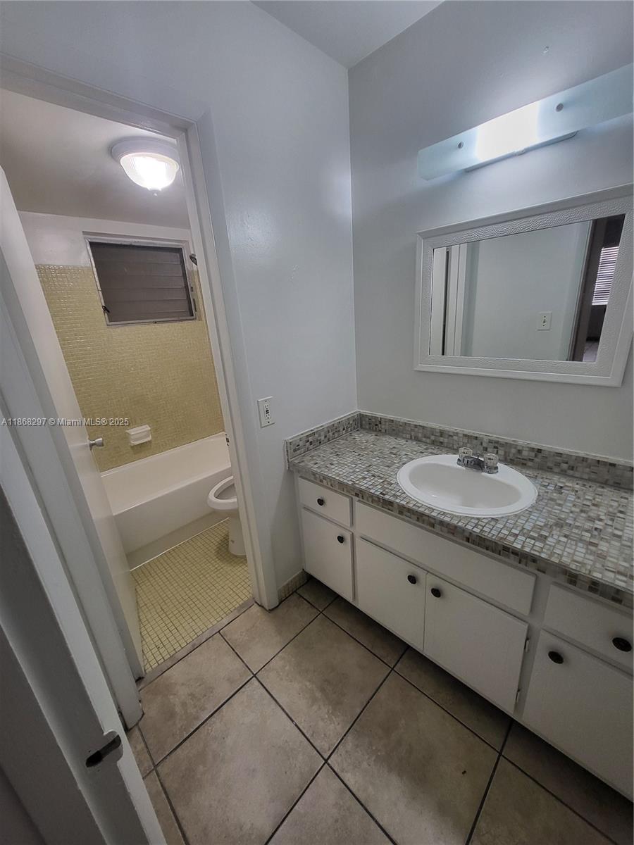 1175 Normandy Drive, Unit 2D Miami Beach, FL 33141 - Photo 9 of 13 a bathroom with a granite countertop sink and a mirror