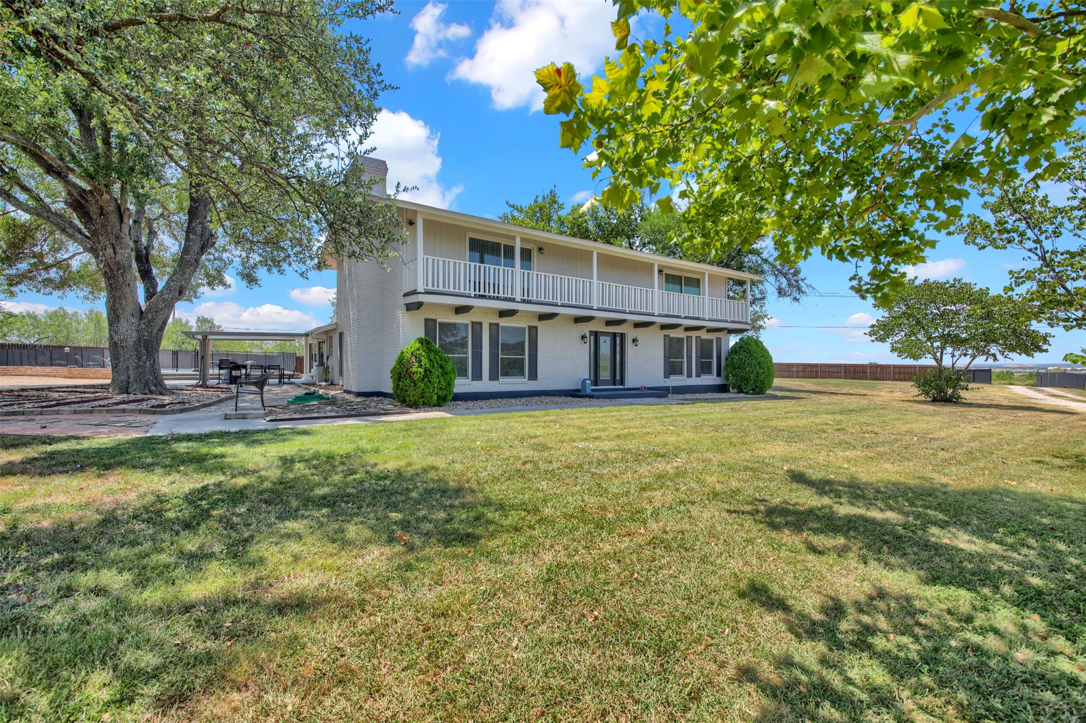 550 C.Bud Stockton Loop Jarrell, TX 76537 - Photo 1 of 37 Back of house with a patio area, a balcony, a chimney, and brick siding