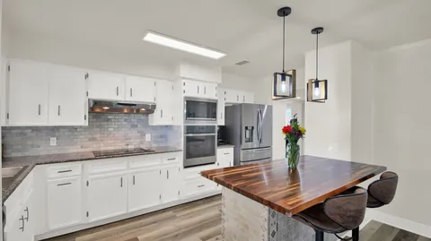 a kitchen with stainless steel appliances granite countertop a sink refrigerator and cabinets