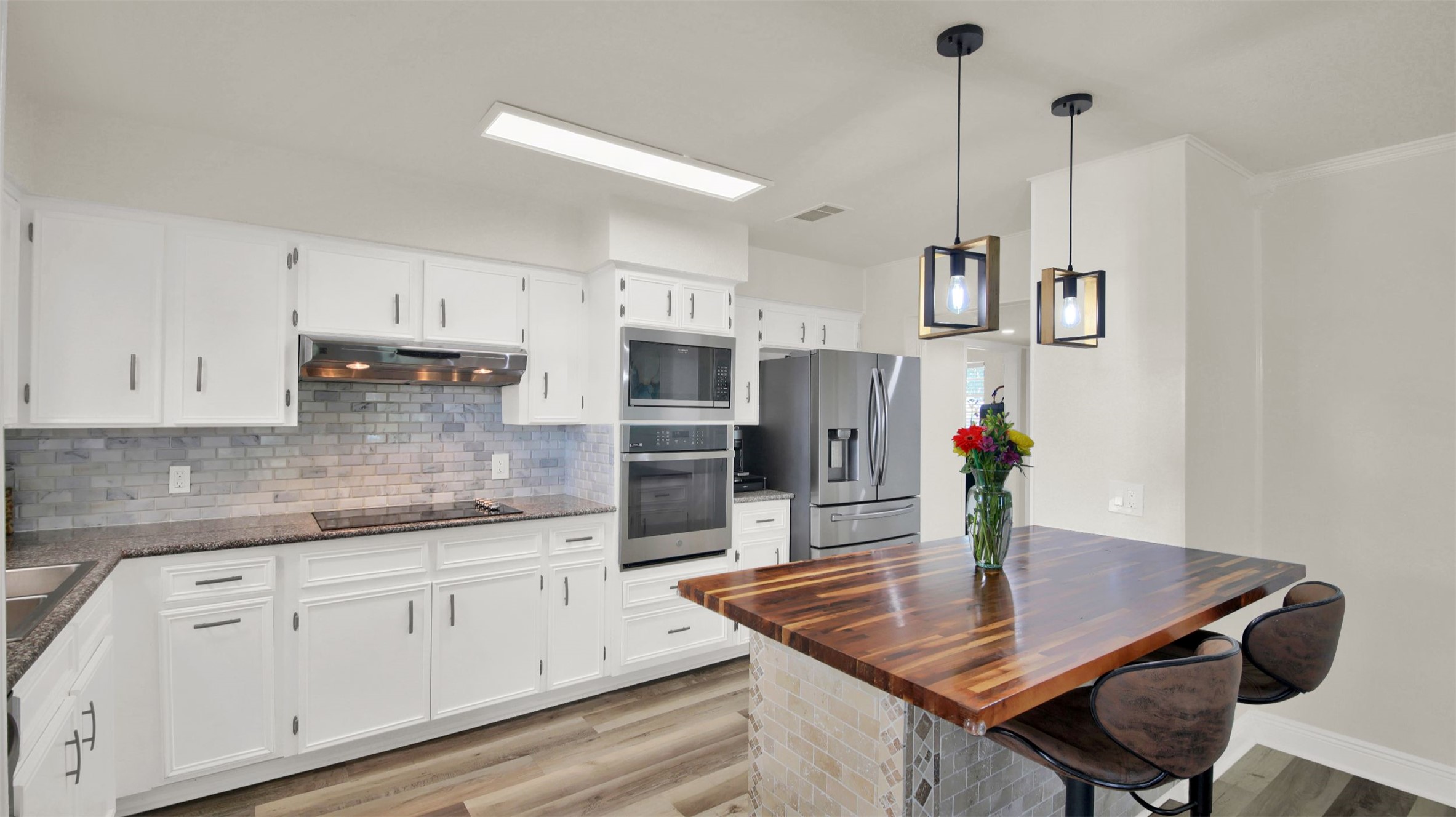550 C.Bud Stockton Loop Jarrell, TX 76537 - Photo 13 of 37 Kitchen with backsplash, a kitchen breakfast bar, white cabinets, hanging light fixtures, and stainless steel appliances
