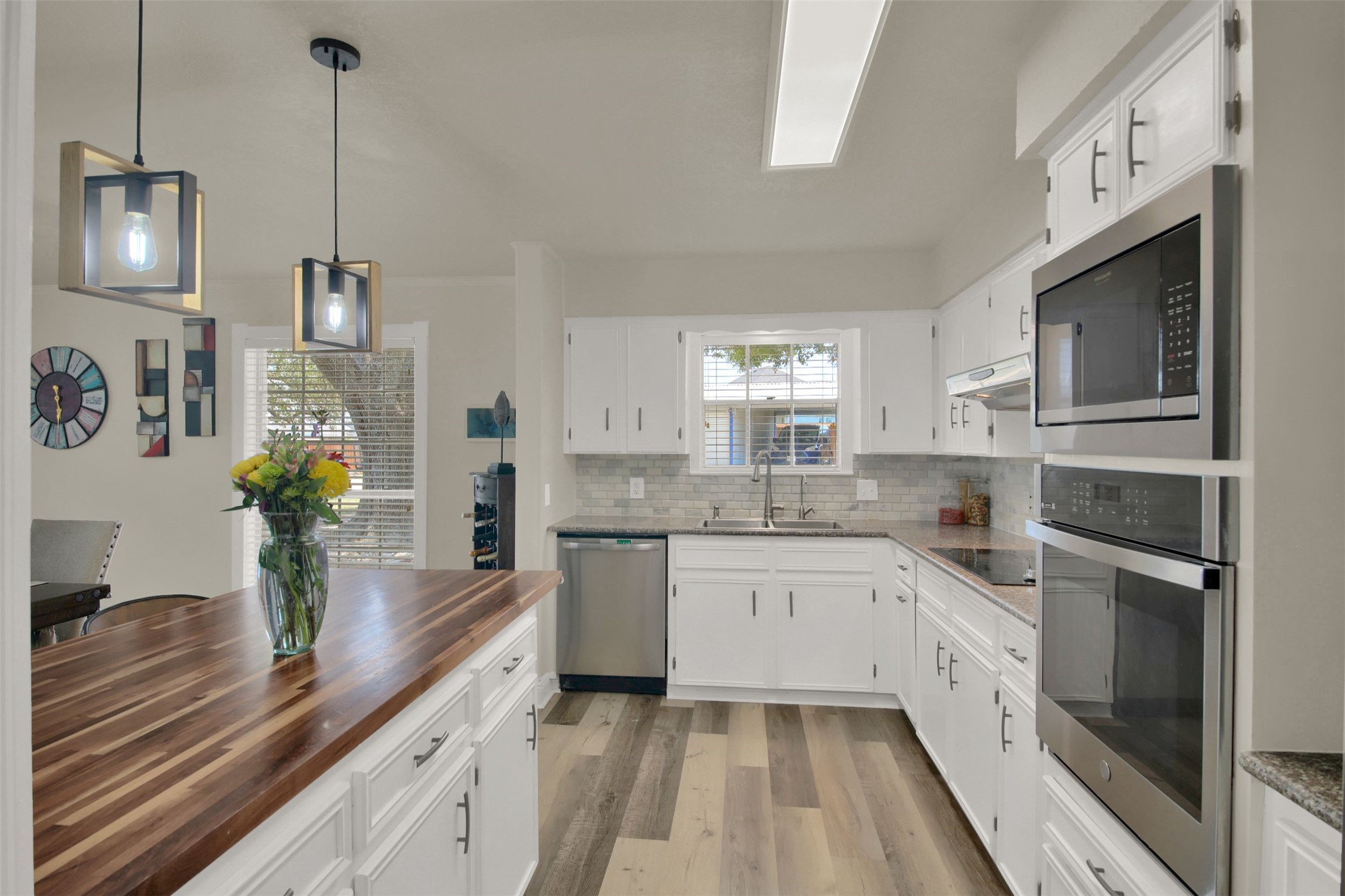 550 C.Bud Stockton Loop Jarrell, TX 76537 - Photo 14 of 37 Kitchen featuring appliances with stainless steel finishes, backsplash, light wood-type flooring, white cabinetry, and wood counters