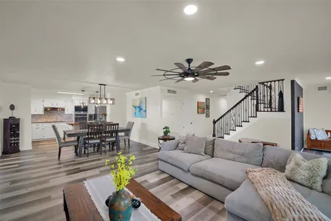 a living room with furniture kitchen view and a wooden floor