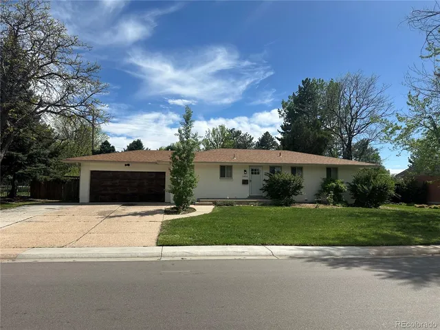 a front view of a house with a garden and trees