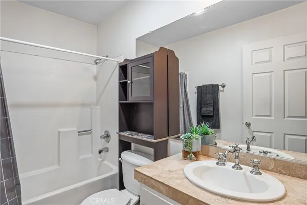 a bathroom with a granite countertop sink a toilet and shower