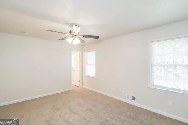 an empty room with a window and a fan