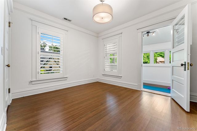 an empty room with wooden floor windows and entrance