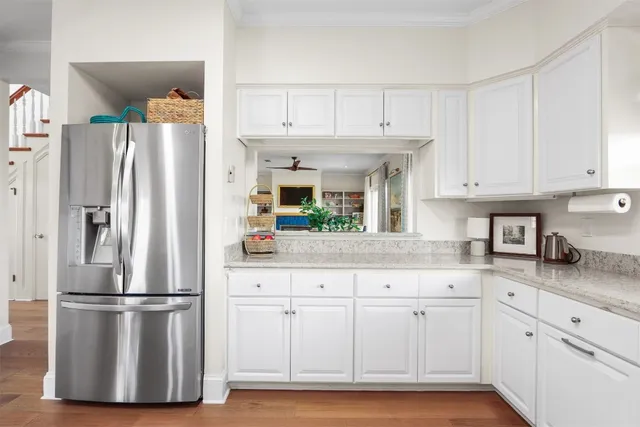 a kitchen with granite countertop a refrigerator a sink and white cabinets