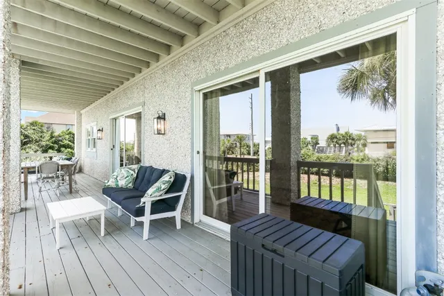 a balcony with wooden floor table and chairs