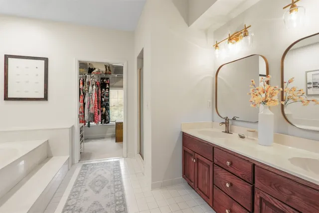 a spacious bathroom with a double vanity sink a mirror and a bathtub