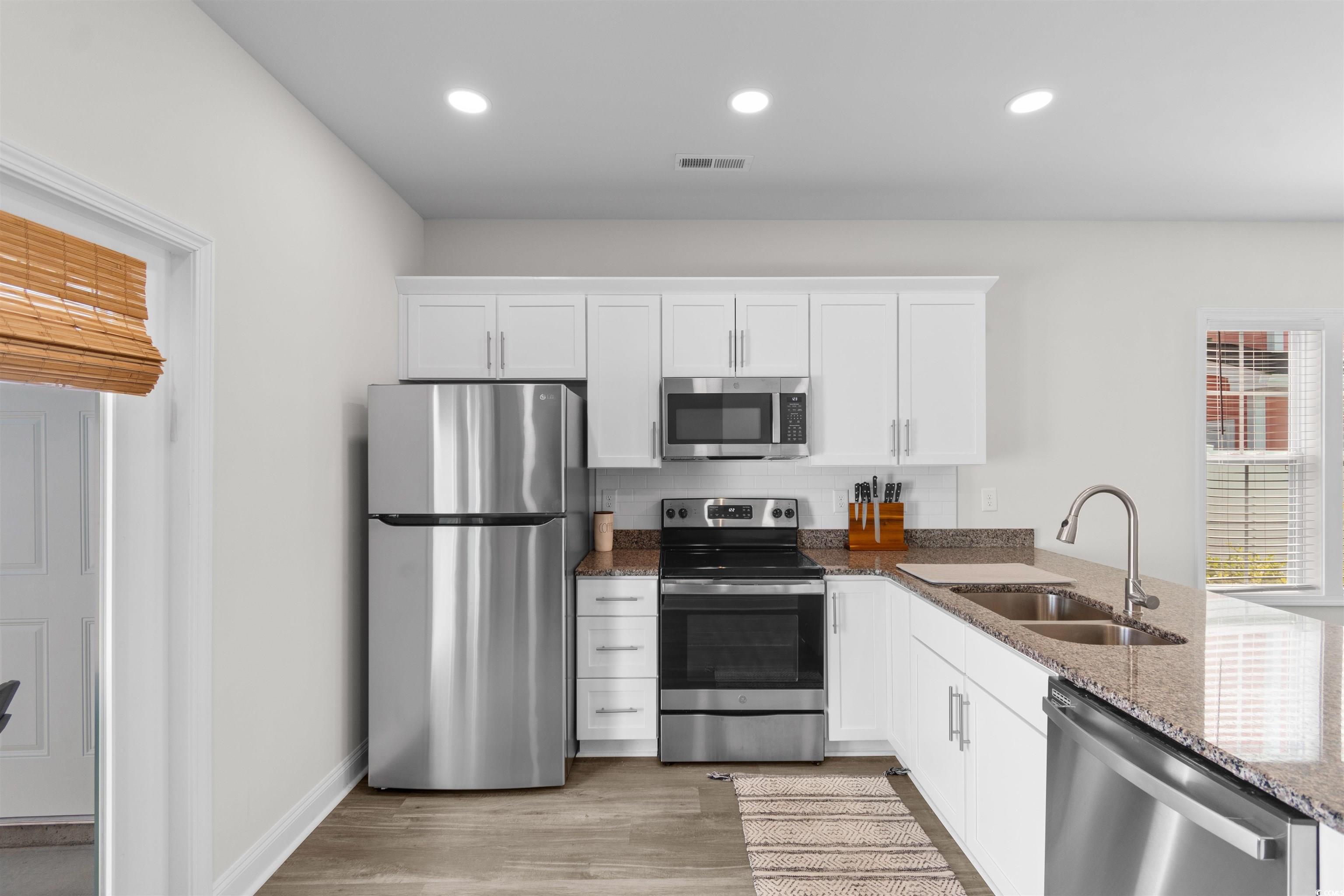 804 Moen Place, Unit F Myrtle Beach, SC 29577 - Photo 7 of 34 Kitchen with appliances with stainless steel finishes, dark stone countertops, white cabinetry, recessed lighting, and light wood-style floors