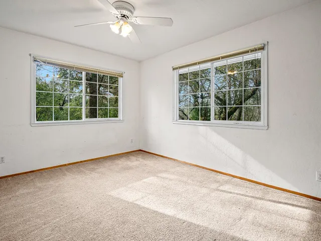 an empty room with a window and a ceiling fan