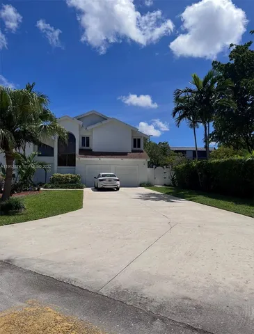 a view of a house with a yard and a large tree