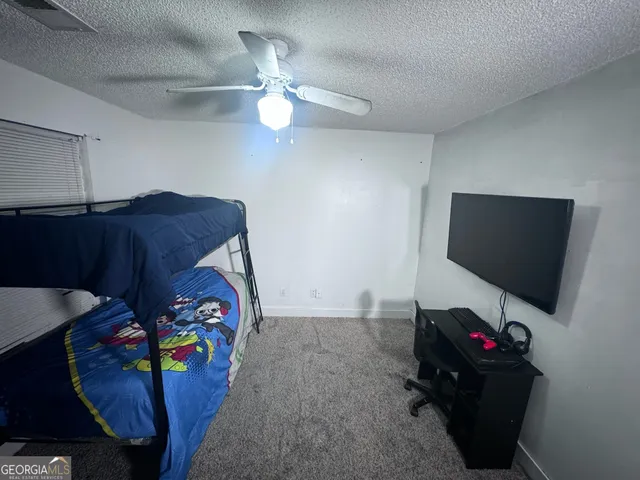 a bedroom with a bed and a flat tv screen on the dresser
