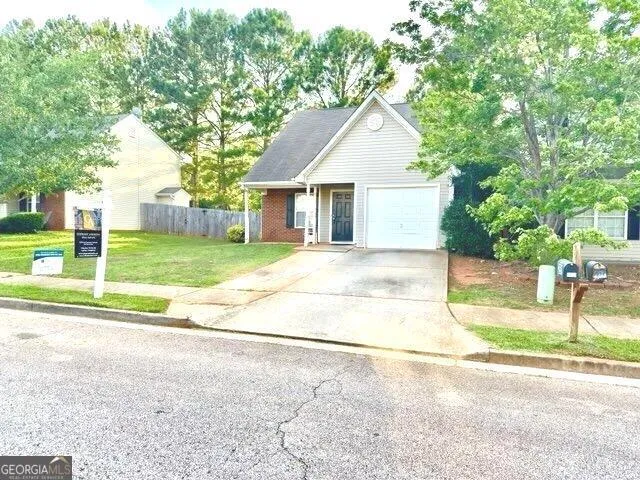 a view of a house with a yard and large tree