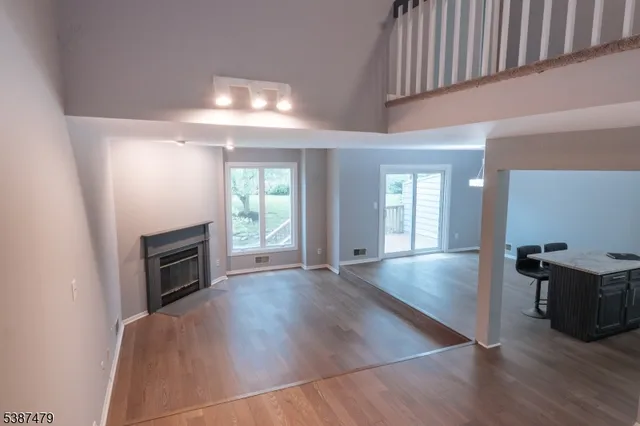 an empty room with wooden floor fireplace and windows