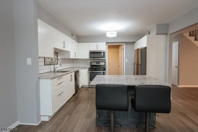 a kitchen with stainless steel appliances kitchen island granite countertop a table chairs sink and cabinets