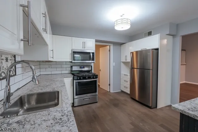 a kitchen with stainless steel appliances granite countertop a refrigerator a stove a sink and a microwave