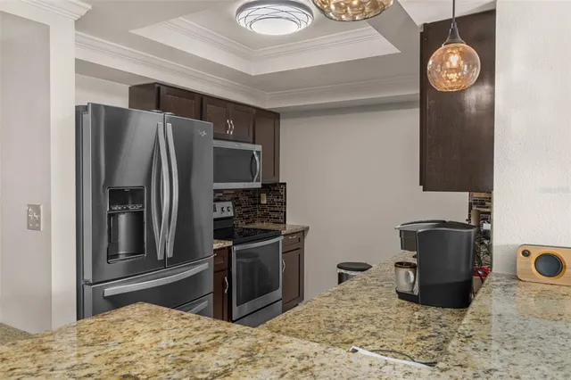 a kitchen with stainless steel appliances granite countertop a refrigerator a stove and a sink