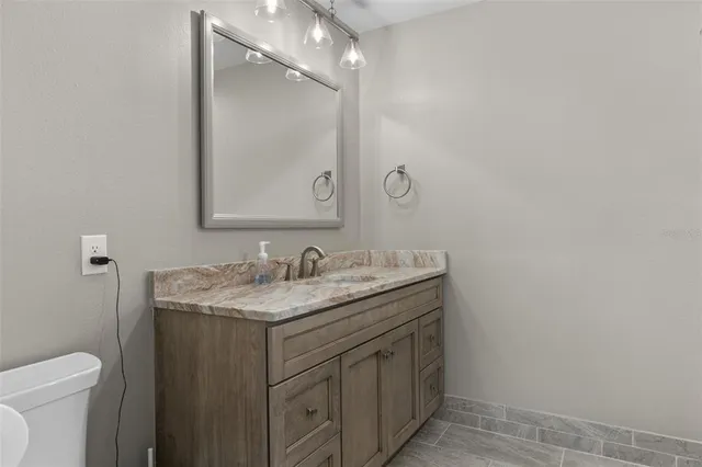 a bathroom with a granite countertop sink a toilet and a mirror